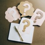 Flat lay of question mark paper crafts on a notebook, symbolizing questions and ideas.